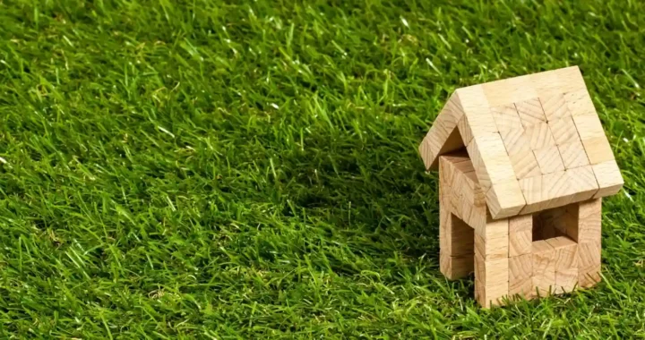 Miniatur struktur rumah kayu di atas rumput hijau