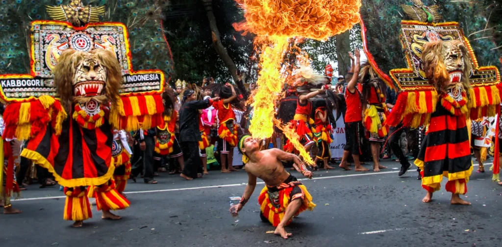 dua orang memakai kostum berkepala singa dan satu orang menyemburkan api dari mulut