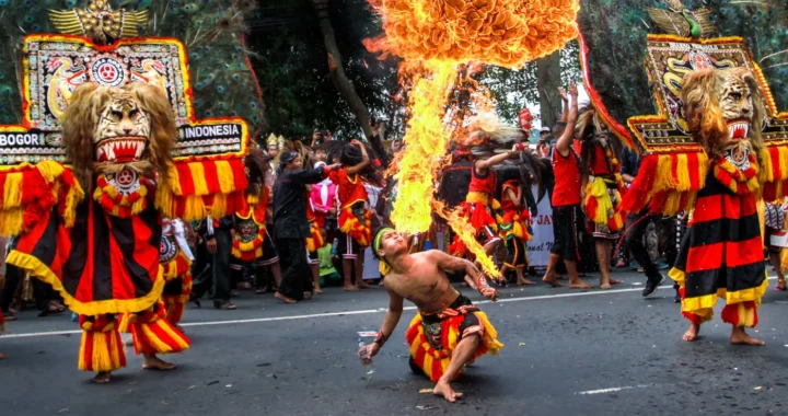 dua orang memakai kostum berkepala singa dan satu orang menyemburkan api dari mulut