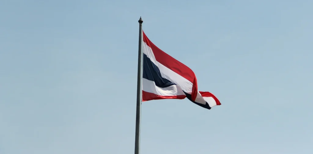 bendera Thailand di tiang menghadap langit biru