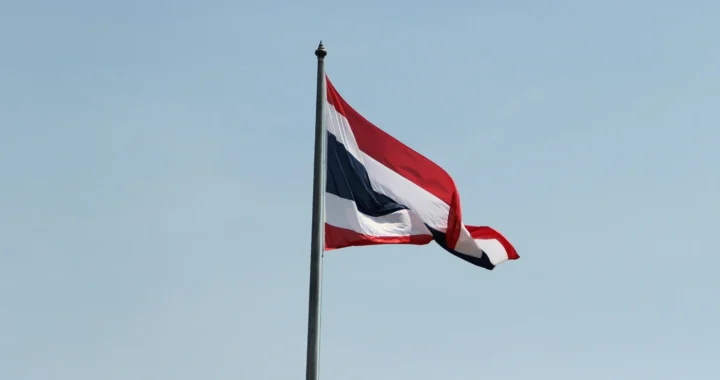 bendera Thailand di tiang menghadap langit biru