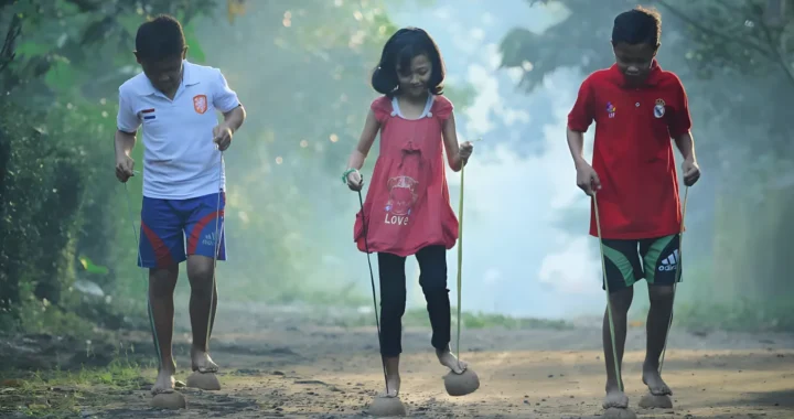 dua anak laki-laki dan seorang anak perempuan di tengah bermain engklek.