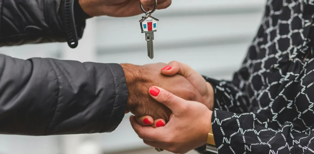 seseorang menyerahkan kunci rumah kepada orang lain