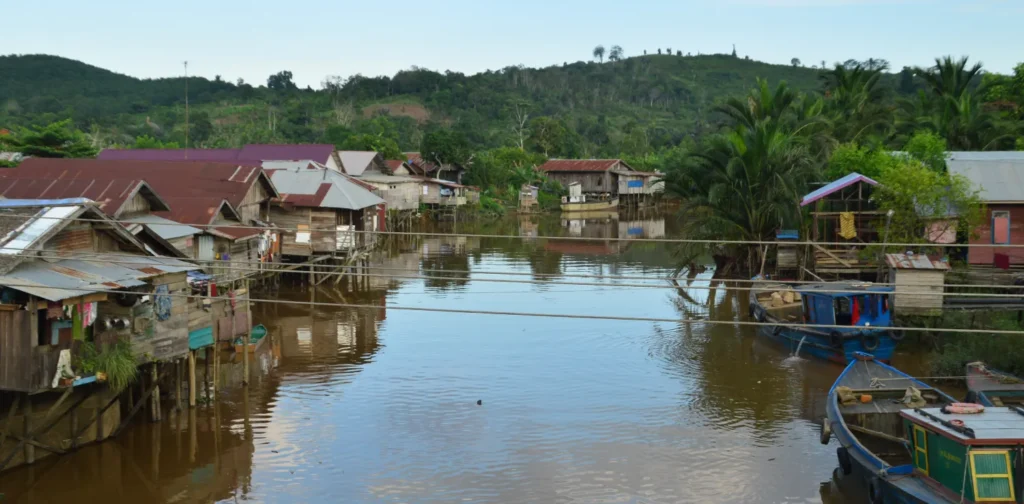 deretan rumah di sisi kanan dan kiri sungai dengan latar bukit hijau