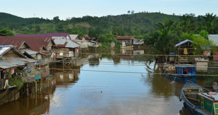 deretan rumah di sisi kanan dan kiri sungai dengan latar bukit hijau