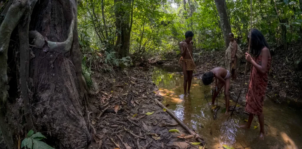 empat orang Suku Anak Dalam yang berada di sungai kecil dalam hutan