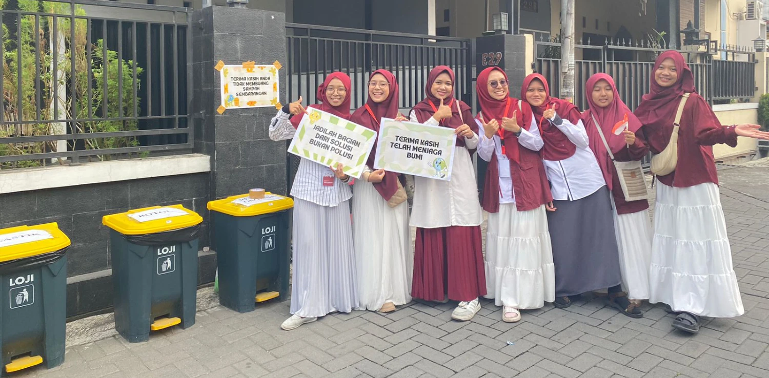 tujuh perempuan berjilbab berfoto bersama di dekat tong sampah