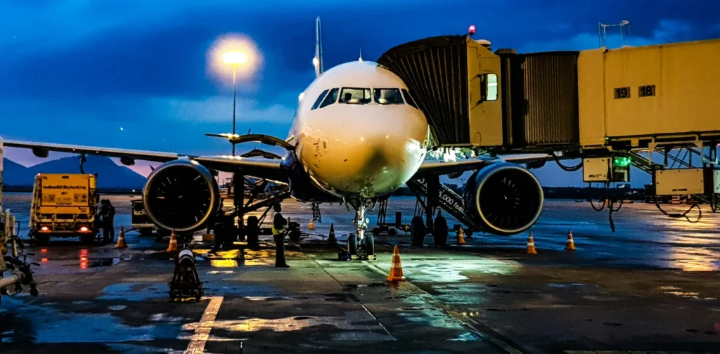 pesawat berwarna putih sedang parkir di dekat garbarata bandara