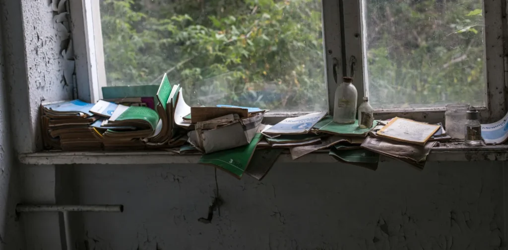 Tumpukan buku terbengkalai di samping jendela.