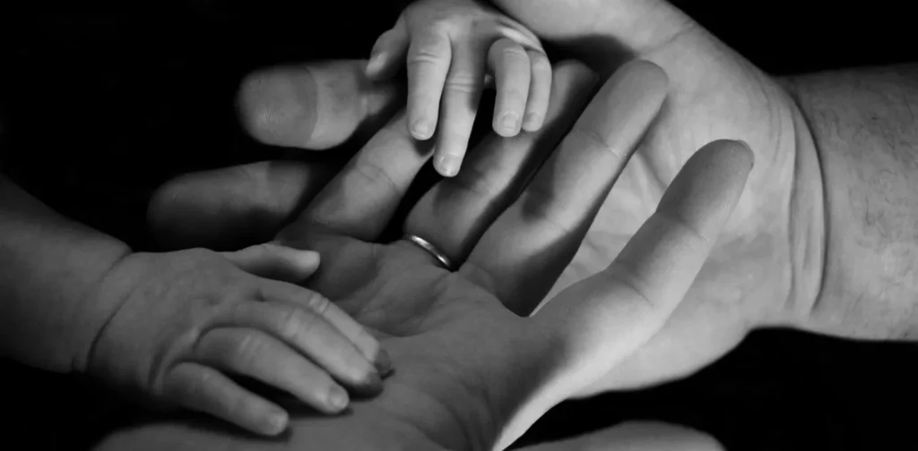 foto hitam putih tangan orang dewasa dan bayi bersentuhan