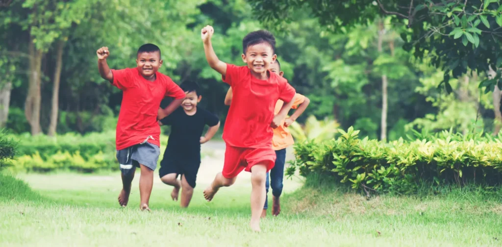 empat anak yang berlari ke arah kamera di taman berumput