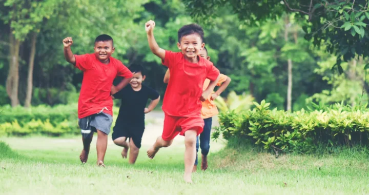 empat anak yang berlari ke arah kamera di taman berumput