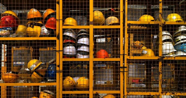 rak berjaring yang diisi dengan helm-helm proyek berwarna kuning dan merah