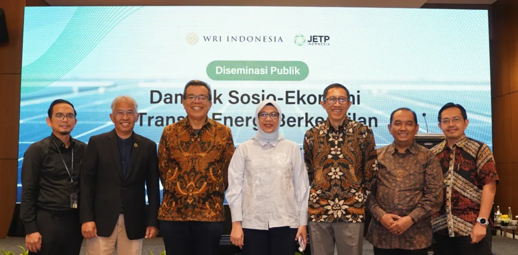 7 orang berfoto bersama di hadapan laya presentasi