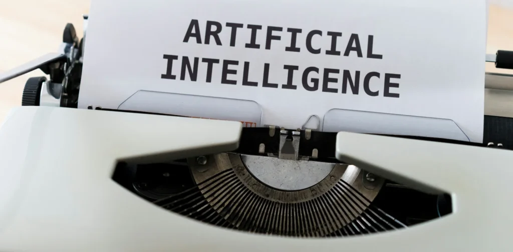 mesin tik dengan kertas bertuliskan “artificial intelligence”