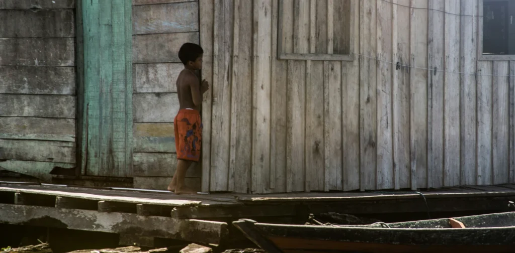 seorang anak berdiri di sebuah rumah kayu