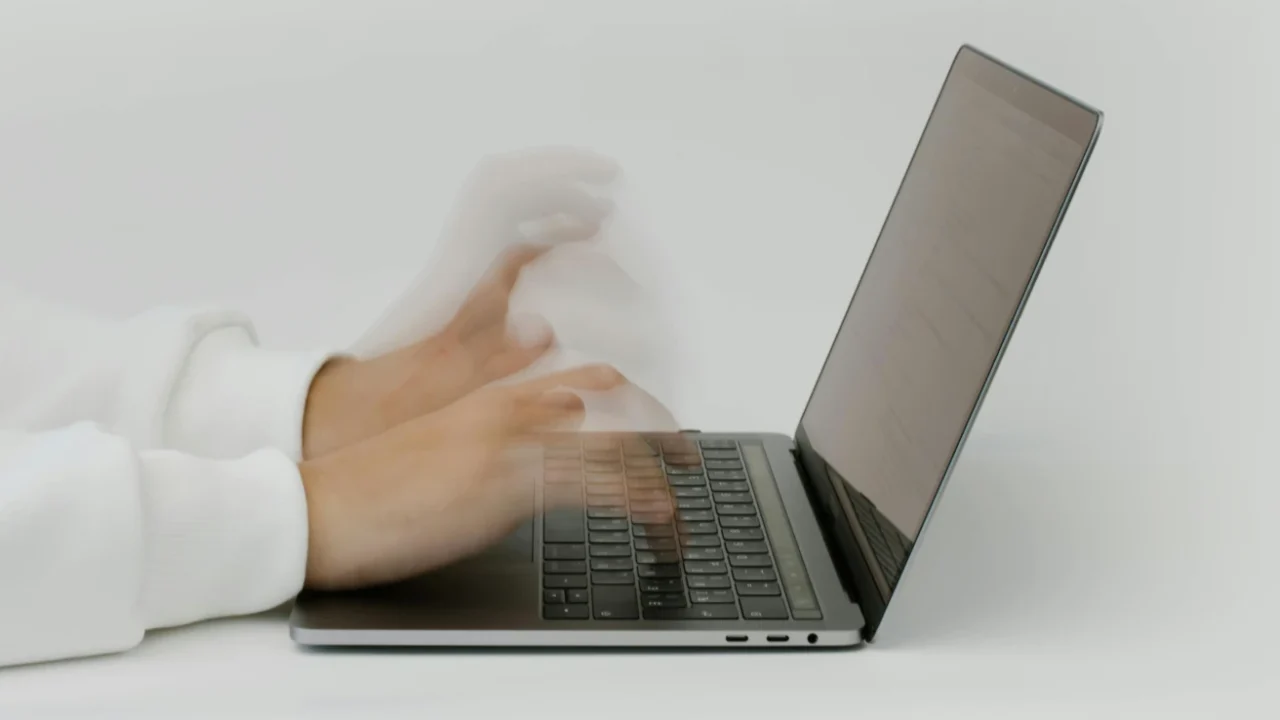 tampak samping tangan dengan tampilan yang buram sedang mengetik di laptop