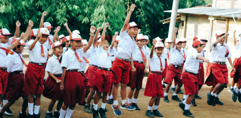 sekelompok siswa sd mengenakan seragam merah putih sedang berbaris sambil mengepalkan tangan ke atas