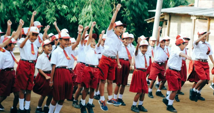 sekelompok siswa sd mengenakan seragam merah putih sedang berbaris sambil mengepalkan tangan ke atas