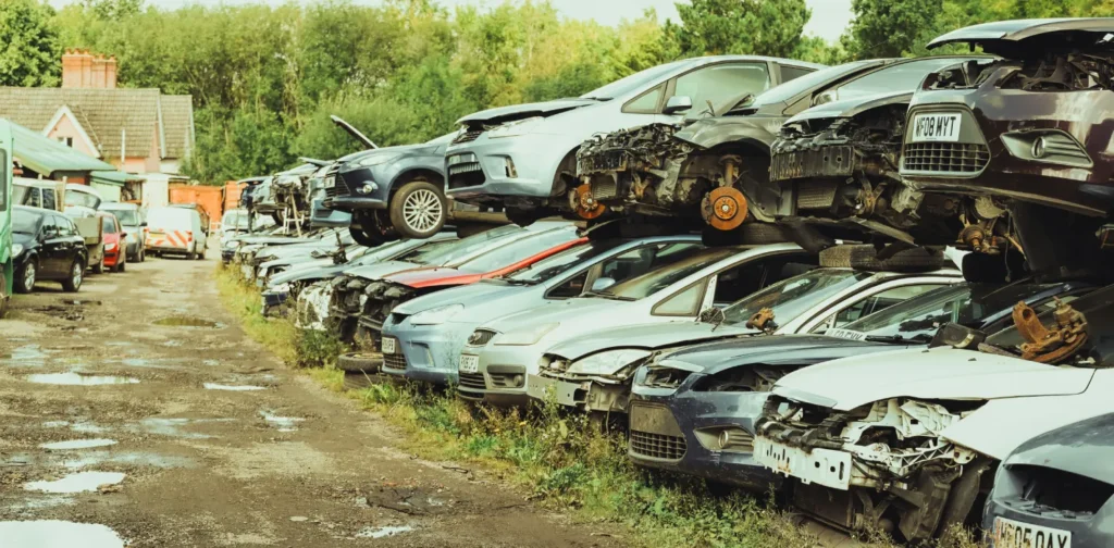 tumpukan mobil tua yang terbengkalai di sebuah tempat.