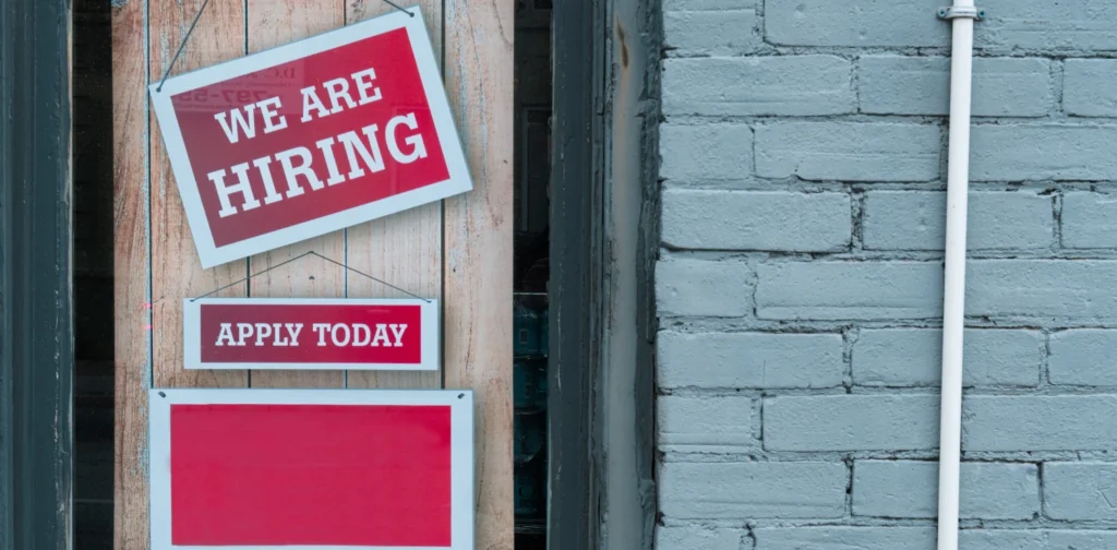 sebuah papan pengumuman bertuliskan ‘we are hiring’ tergantu di depan pintu