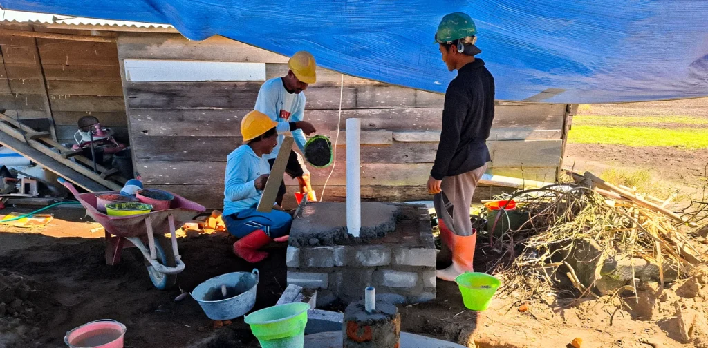 tiga pria sedang membangun fasilitas biogas