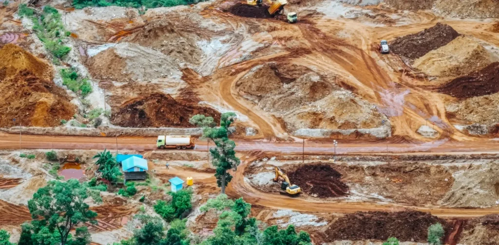 foto udara kawasan dengan lahan yang ditambang, dengan beberapa truk