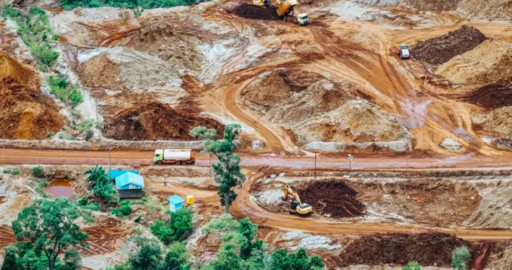 foto udara kawasan dengan lahan yang ditambang, dengan beberapa truk