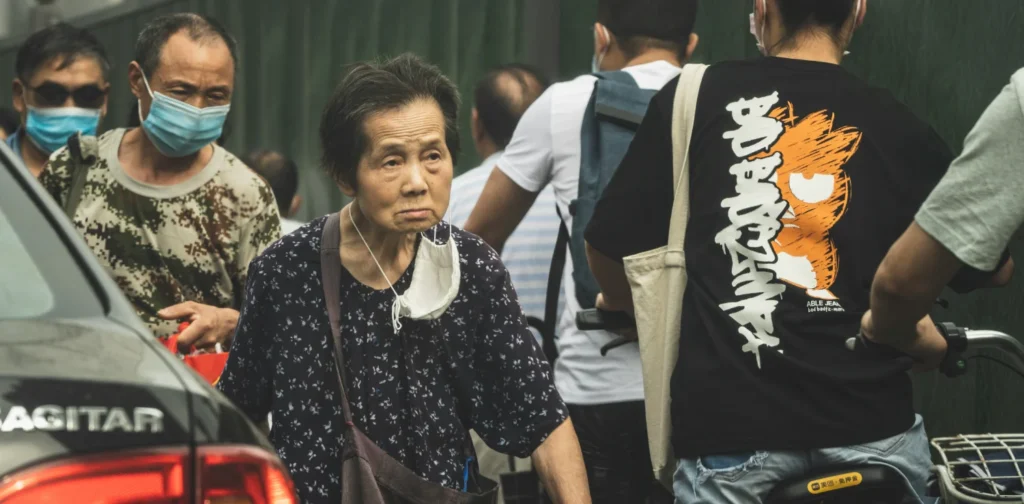 seorang nenek berbaju hitam berjalan di antara orang-orang