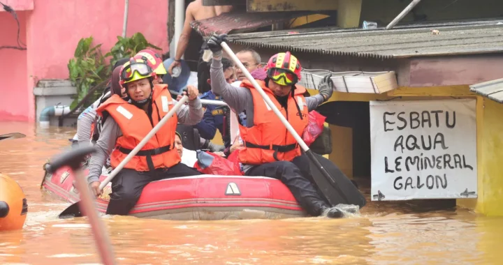 beberapa orang mendayung perahu di permukiman saat banjir.