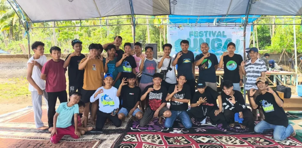 sekelompok orang berfoto bersama dengan sebagian berdiri dan sebagian berjongkok.