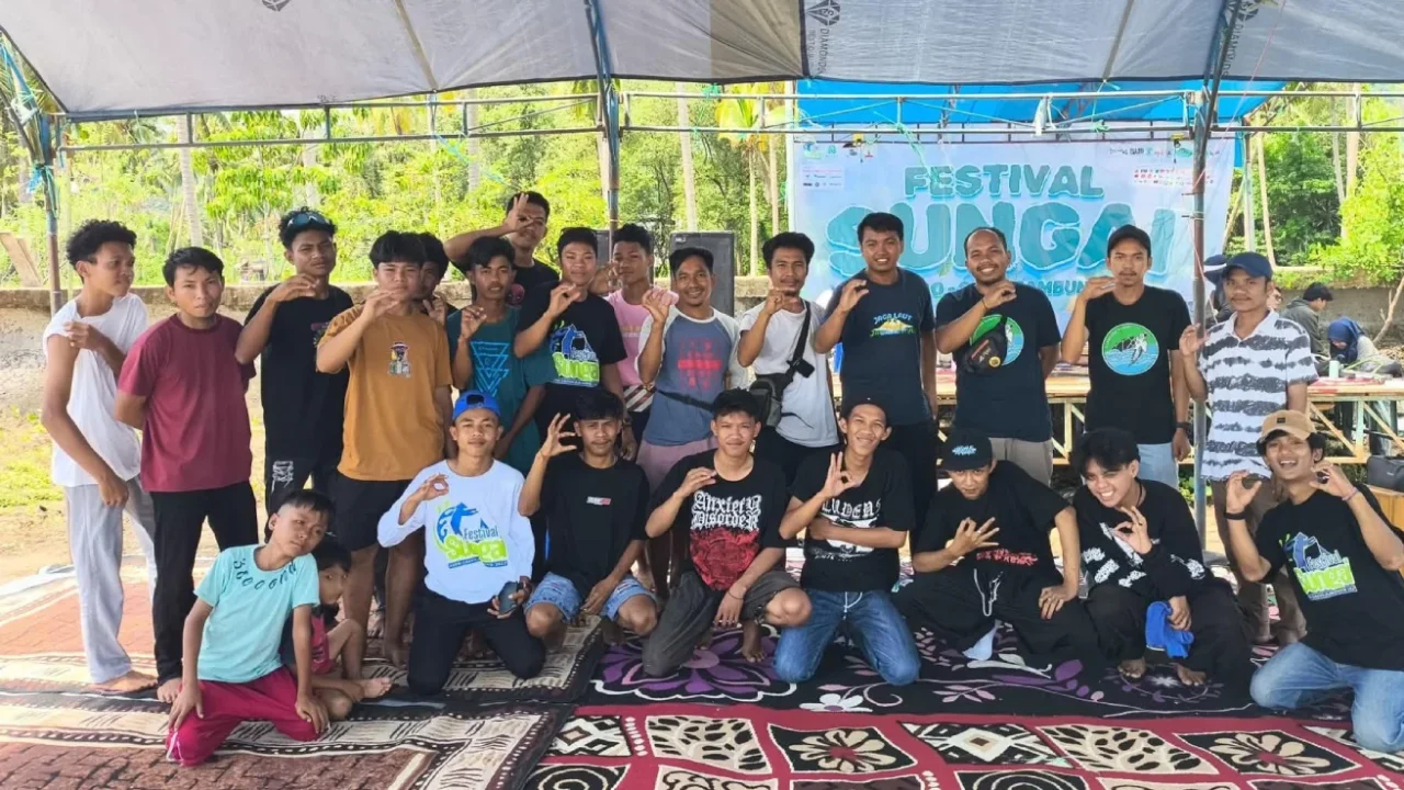 sekelompok orang berfoto bersama dengan sebagian berdiri dan sebagian berjongkok.