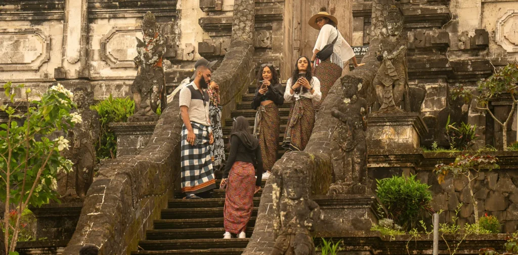 sekelompok orang berdiri di tangga depan kuil.