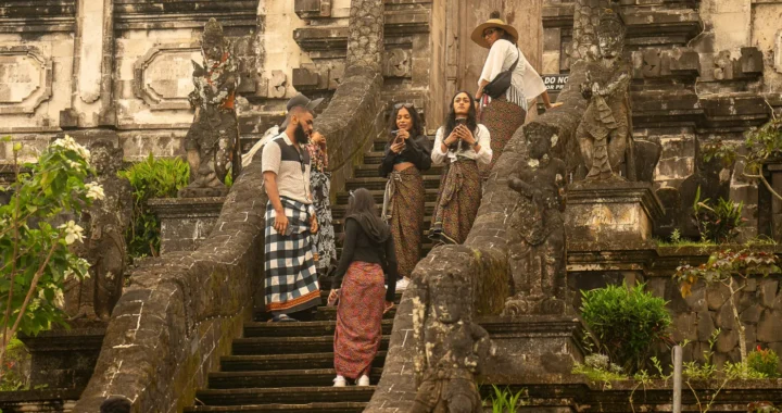sekelompok orang berdiri di tangga depan kuil.