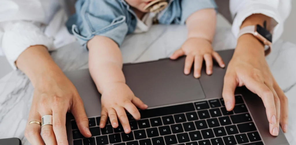 tangan ibu dan bayi di atas keyboard laptop