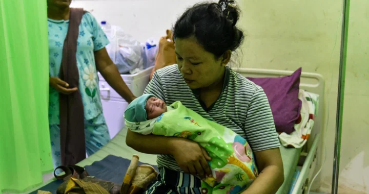 seorang ibu menggendong bayi di atas kasur tempat tidur