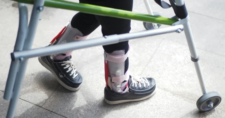 sepasang kaki yang memakai alat bantu berupa sepatu dan kruk