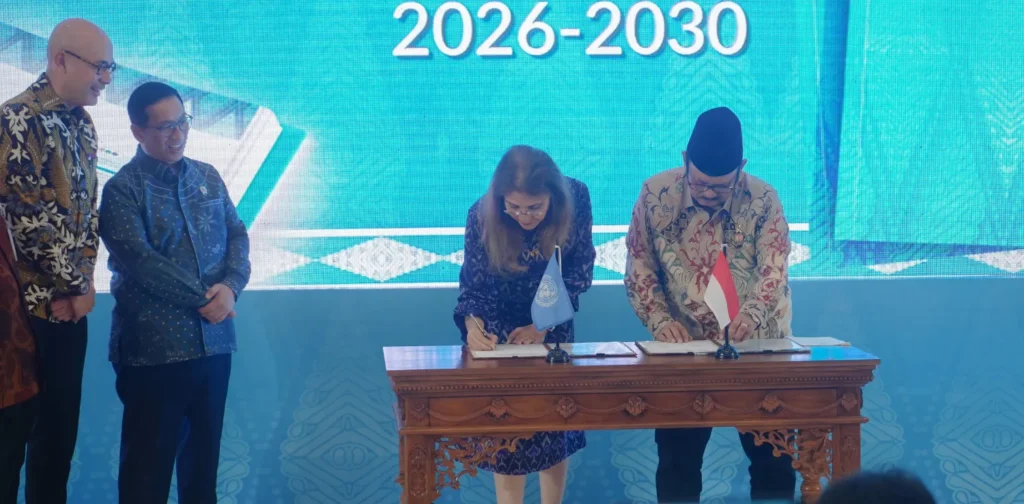 dua orang sedang menandatangani dokumen di atas meja