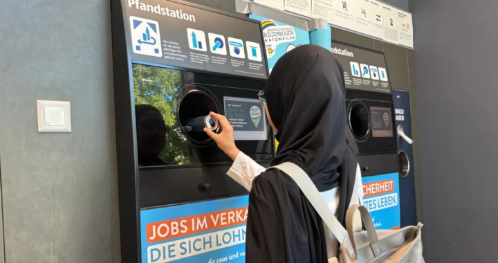 seorang perempuan berjilbab memasukkan kaleng minuman ke dalam mesin daur ulang pfandstation.