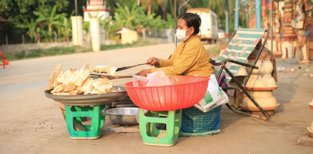 seorang perempuan sedang menggoreng kerupuk yang ditaruh di atas tampah