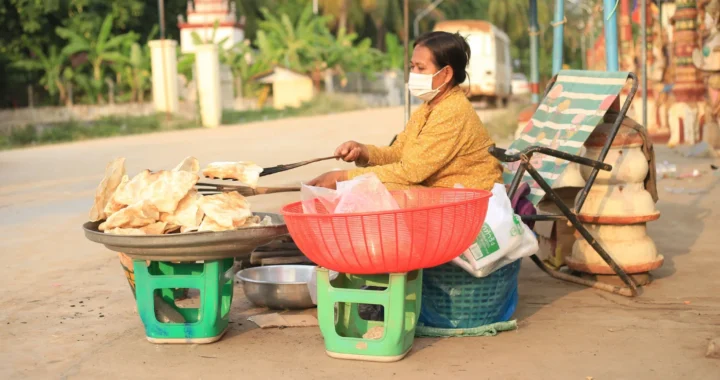 seorang perempuan sedang menggoreng kerupuk yang ditaruh di atas tampah