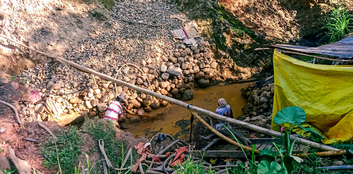 dua orang di bawah galian tanah yang berlumpur
