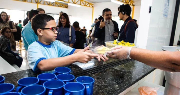 Seorang anak berkacamata menerima piring berisi makanan.