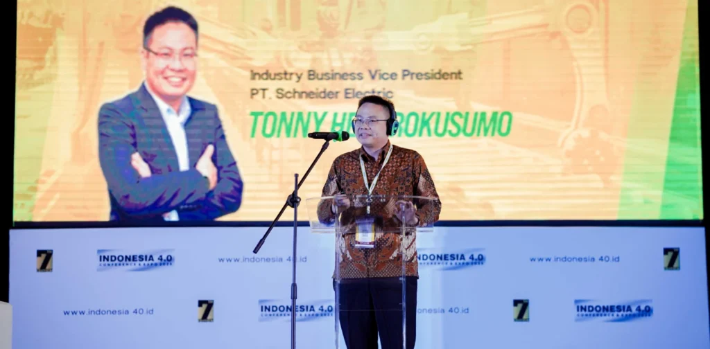 seorang pria berbatik dengan headset di kepala sedang berdiri di podium