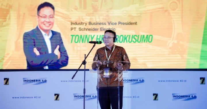 seorang pria berbatik dengan headset di kepala sedang berdiri di podium