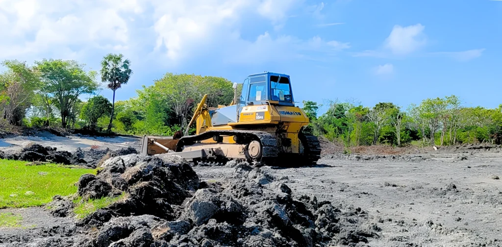 sebuah alat berat di atas lahan hitam