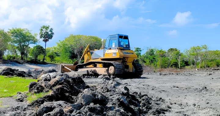 sebuah alat berat di atas lahan hitam