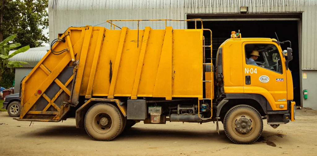 truk sampah kuning yang diparkir di depan fasilitas pengolahan sampah