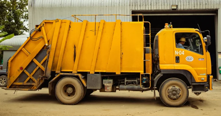truk sampah kuning yang diparkir di depan fasilitas pengolahan sampah