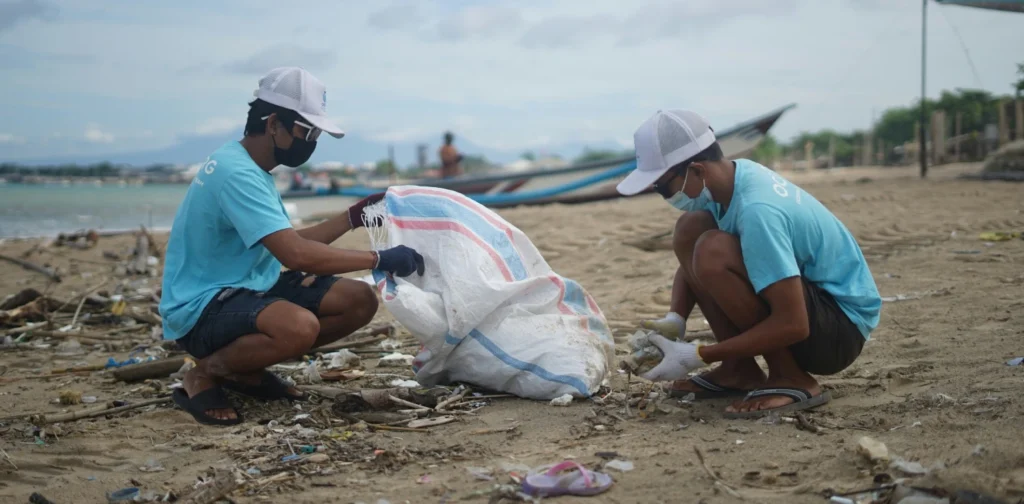 dua pria mengumpulkan sampah di pantai